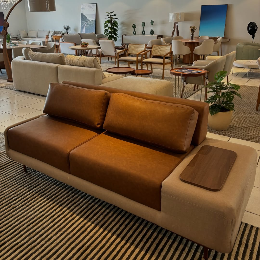 Sofá em tons caramelo e bege com apoio lateral em ambiente decorado